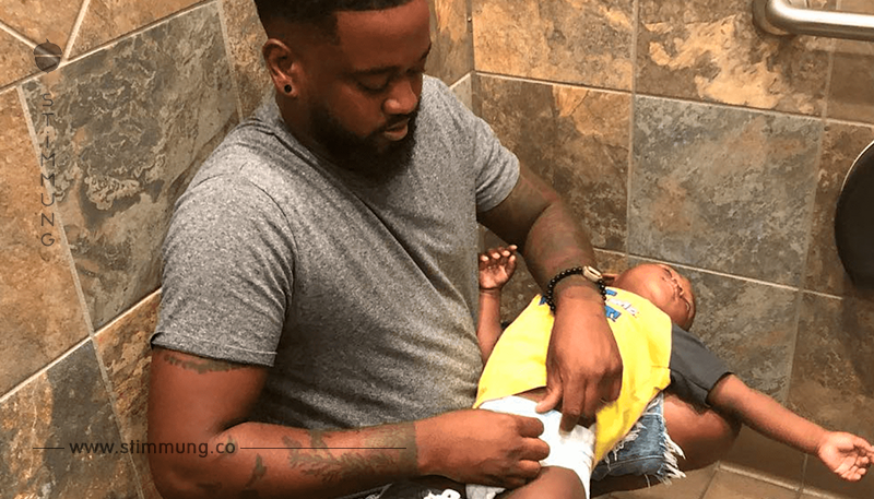 Ein schockierendes virales Video zeigt, wie ein Vater seinem Sohn die Windeln in dem männlichen WC zu wechseln versucht	