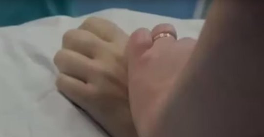 Krankenhausmitarbeiter halten Hand einer Frau, damit sie nicht alleine sterben muss, nachdem die lebenserhaltenden Geräte abgestellt werden