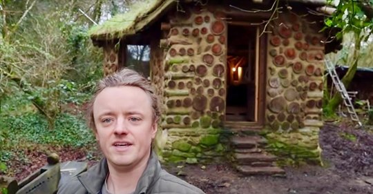 Ein Mann zeigt das Innere seines kleinen Hauses im Wald