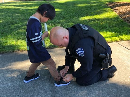Polizist hilft kleinem Jungen mit blutigen Socken.